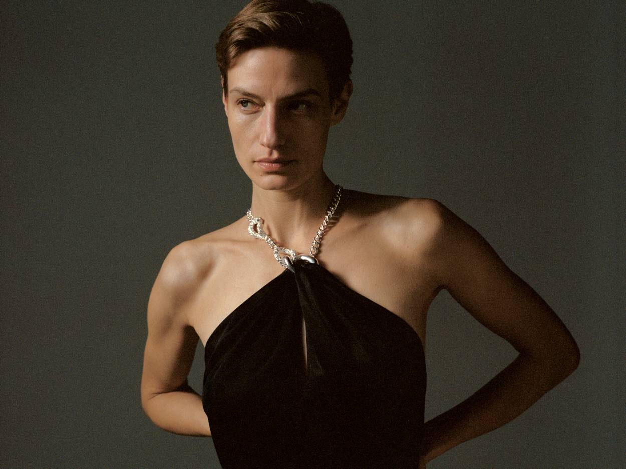 Model wearing black dress with integrated handcrafted jewelry piece around the neckline